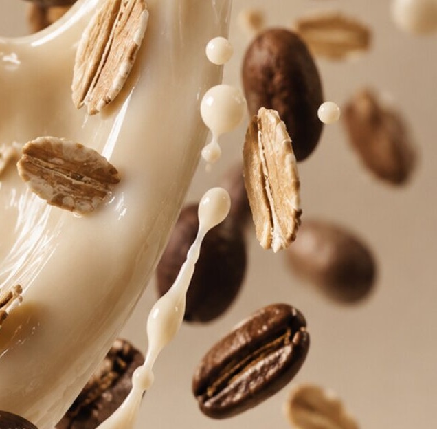 Oat milk splashing with coffee beans and oat flakes